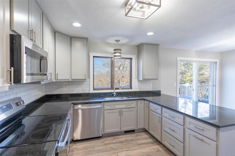 Kitchen with sink, hanging light fixtures, stainless steel appliances, light hardwood / wood-style flooring, and kitchen peninsula