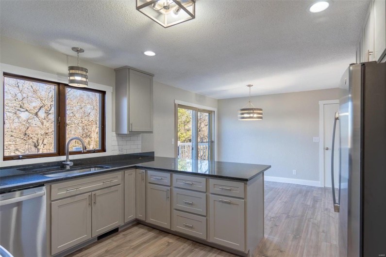Kitchen featuring sink, gray cabinets, appliances with stainless steel finishes, decorative light fixtures, and kitchen peninsula