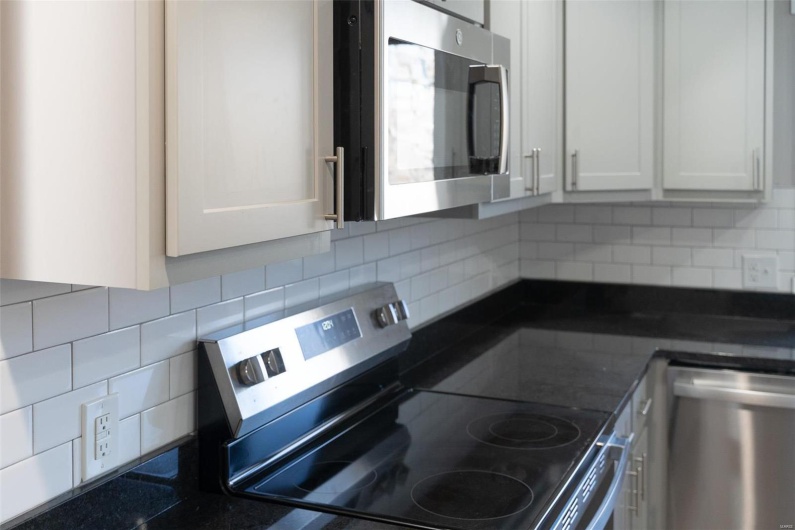 Kitchen featuring decorative backsplash, gray cabinets, and appliances with stainless steel finishes