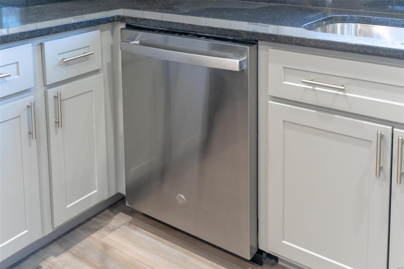 Details featuring stainless steel dishwasher, gray cabinets, and light  / wood-style flooring
