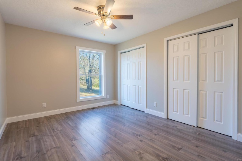 Unfurnished bedroom featuring multiple closets, ceiling fan, and  wood-style floors