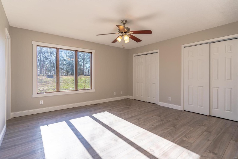 Unfurnished bedroom featuring  wood-style floors, ceiling fan, and multiple closets