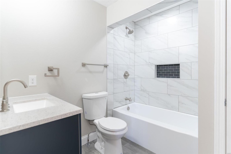 Full bathroom with toilet, vanity, and tiled shower / bath combo