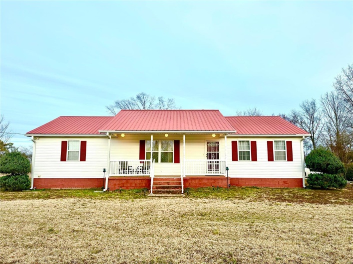 View of front of home featuring covered porch, metal roof, and a front yard