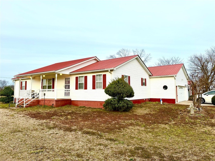 View of front of property with a garage, covered porch, driveway, and metal roof