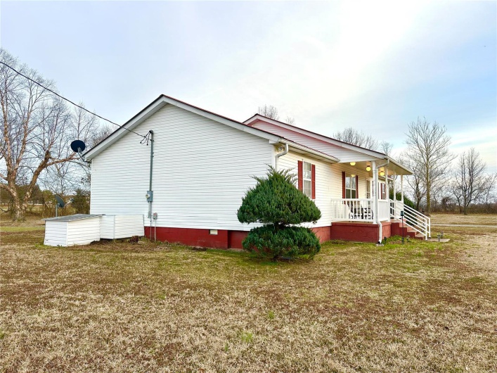 View of side of property with covered porch, crawl space, and a lawn