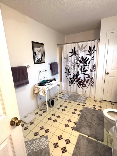 Bathroom with a textured ceiling, a shower with shower curtain, toilet, and tile patterned floors
