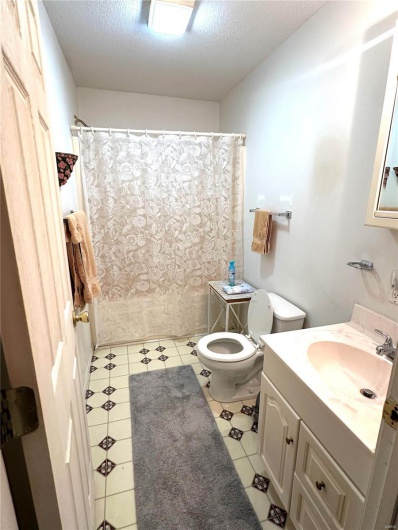 Full bath featuring toilet, shower / tub combo, a textured ceiling, and vanity