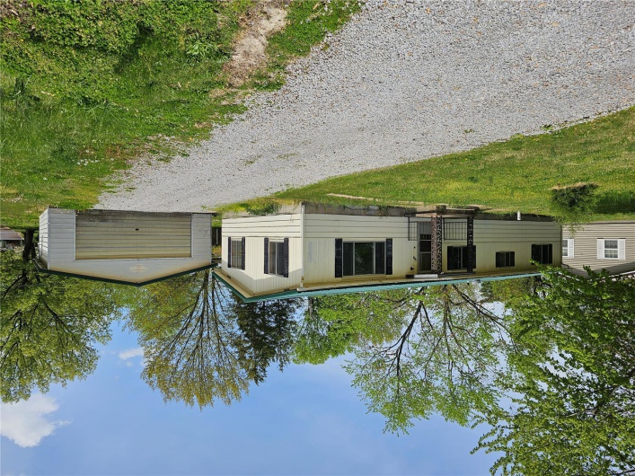 Manufactured / mobile home with a front lawn, an outbuilding, board and batten siding, and a garage