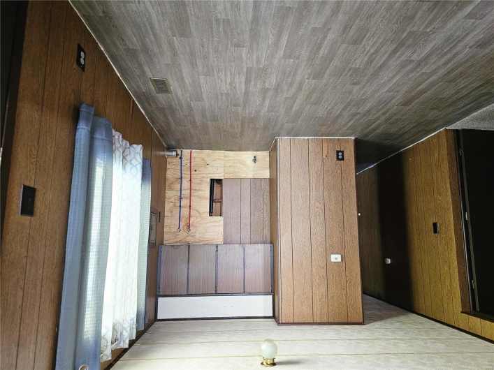 Spare room with visible vents, wood finished floors, and wooden walls