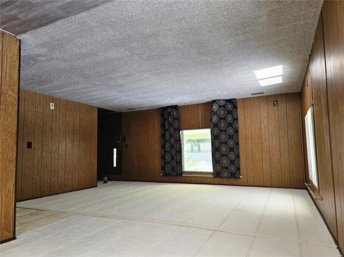 Carpeted spare room featuring wooden walls