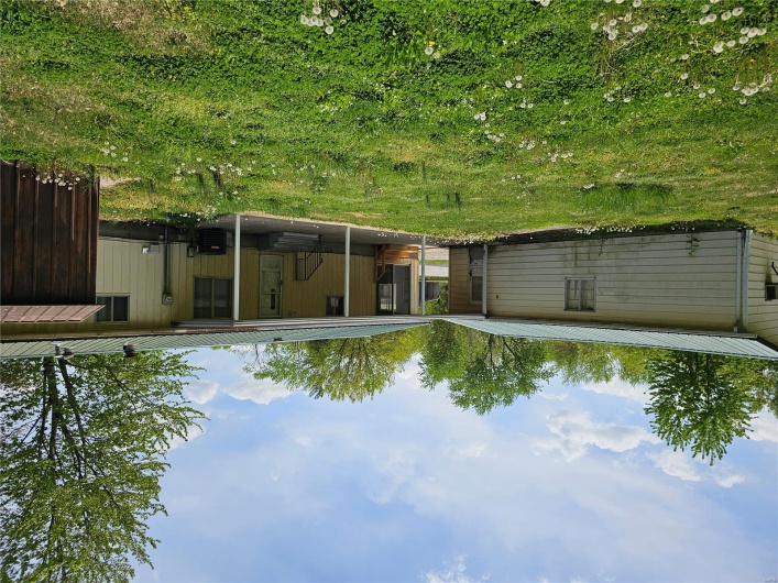 Back of house featuring a lawn, central AC unit, a patio, and metal roof
