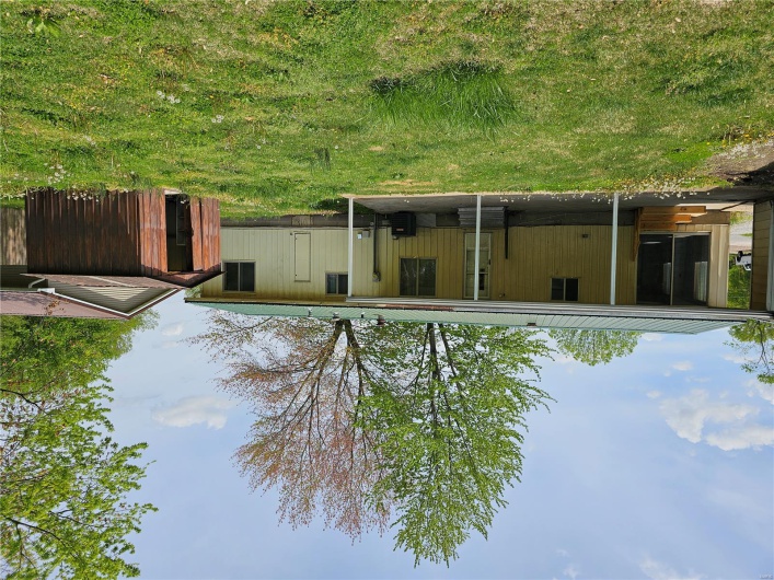 Back of property featuring an outbuilding, a yard, entry steps, metal roof, and a storage unit