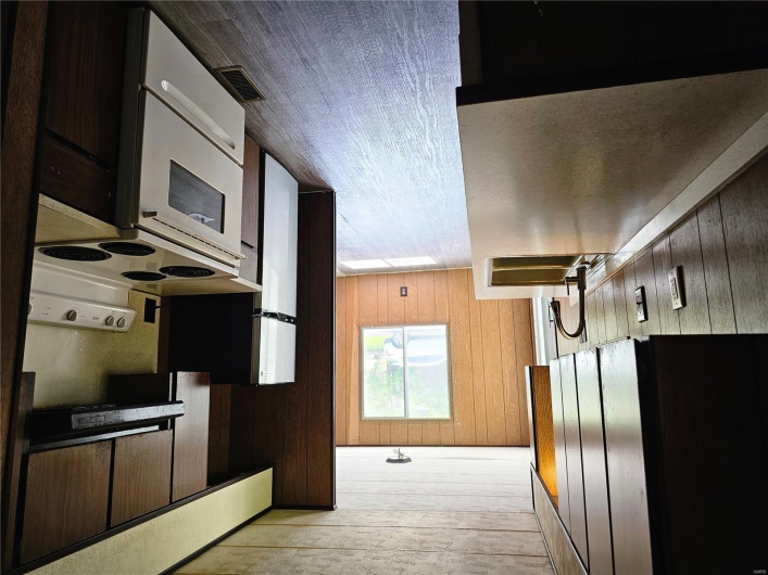 Kitchen with dark wood-style floors, a sink, extractor fan, wood walls, and range