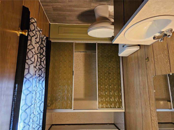 Full bath featuring toilet, vanity, wood finished floors, and combined bath / shower with glass door