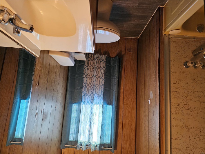 Bathroom with wallpapered walls, wood finished floors, toilet, and vanity