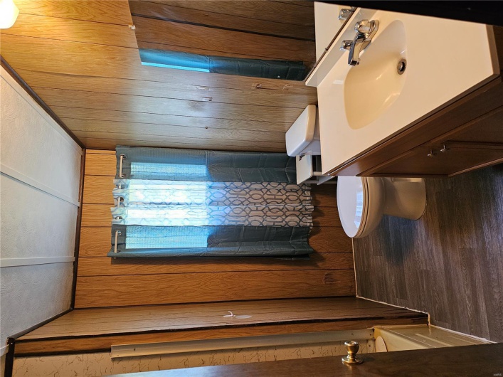 Full bathroom featuring a textured ceiling, toilet, wood finished floors, wooden walls, and vanity