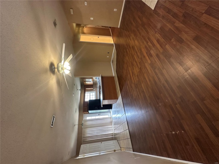 Unfurnished living room with visible vents, baseboards, a textured ceiling, and dark wood-style flooring