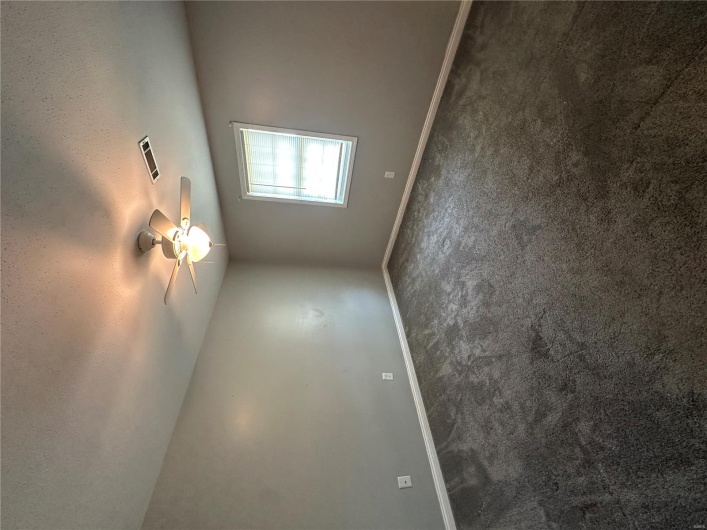 Empty room with dark colored carpet, a textured ceiling, visible vents, baseboards, and a ceiling fan