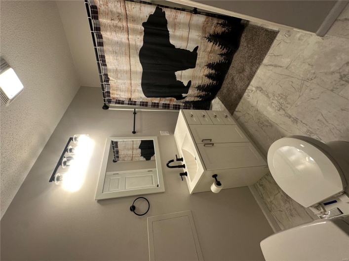 Bathroom with a textured ceiling, marble finish floor, and toilet