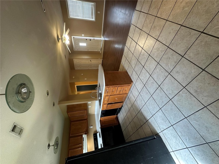 Kitchen featuring a peninsula, extractor fan, light tile patterned floors, and a sink