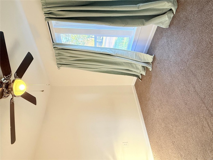 Unfurnished room with dark colored carpet, a ceiling fan, and baseboards