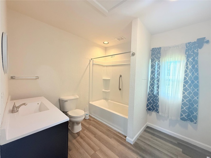 Full bathroom featuring toilet, visible vents, baseboards, wood finished floors, and vanity