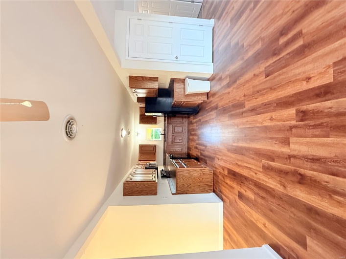 Kitchen with brown cabinets, dark countertops, wood finished floors, visible vents, and fridge
