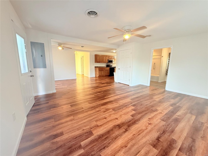 Unfurnished living room with electric panel, a ceiling fan, visible vents, and light wood-style floors