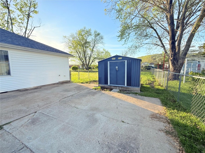View of patio / terrace with fence, an outdoor structure, and a shed