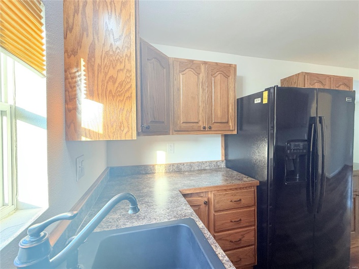 Kitchen featuring black refrigerator with ice dispenser and a sink