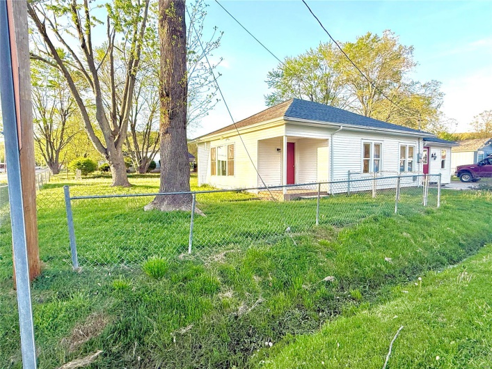 Bungalow featuring roof with shingles, a front lawn, and fence