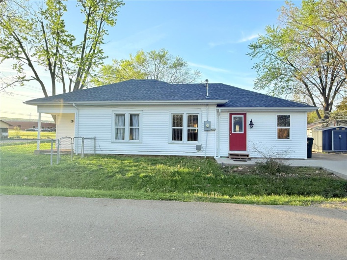 Ranch-style home with a storage shed, roof with shingles, fence, entry steps, and a front yard