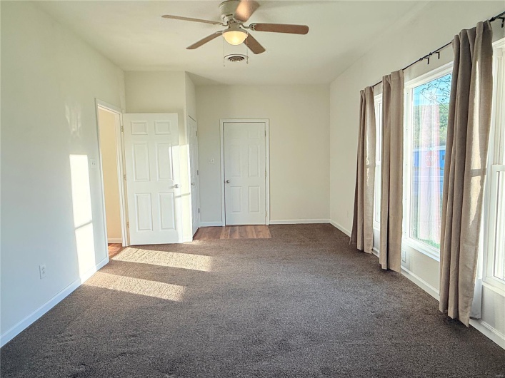 Carpeted spare room with baseboards, a ceiling fan, and visible vents