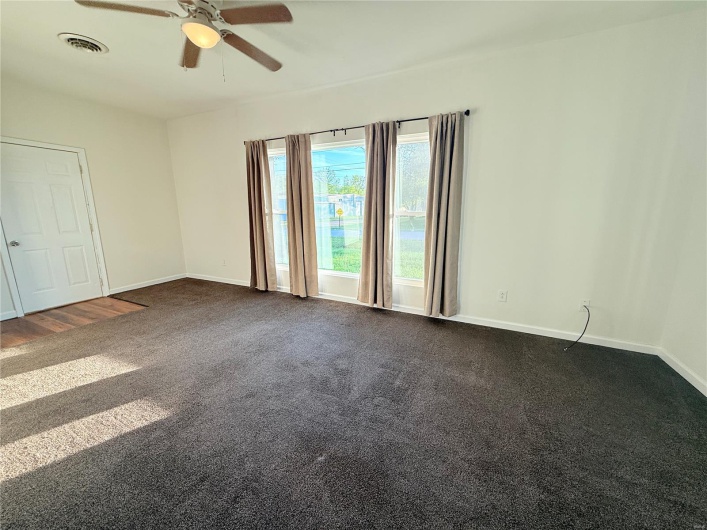Spare room featuring baseboards, dark colored carpet, visible vents, and a ceiling fan