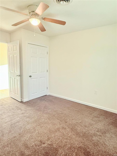 Unfurnished bedroom featuring visible vents, a ceiling fan, baseboards, and carpet
