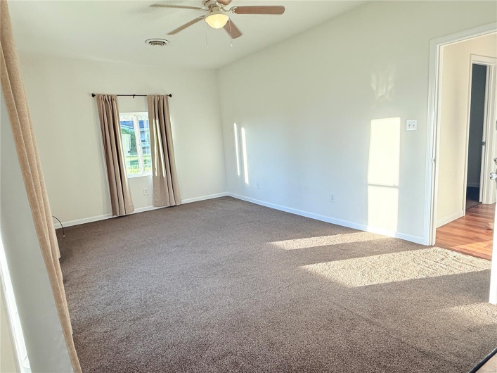 Carpeted empty room featuring visible vents, baseboards, and ceiling fan