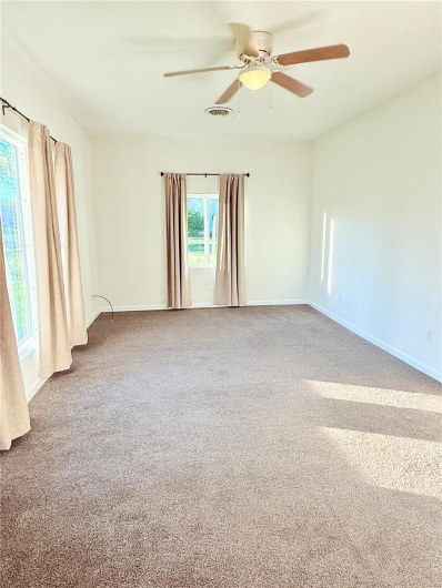 Carpeted empty room featuring visible vents, a ceiling fan, and baseboards