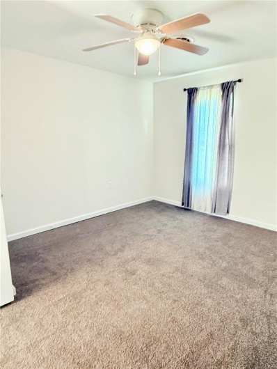 Carpeted spare room with baseboards and a ceiling fan