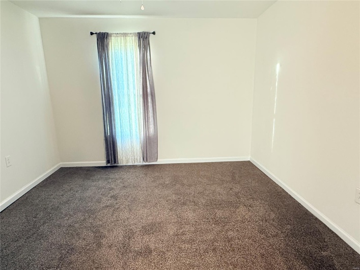 Empty room featuring dark colored carpet and baseboards