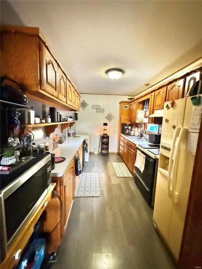 Kitchen featuring stainless steel microwave, dark wood-style flooring, electric range oven, light countertops, and white fridge with ice dispenser