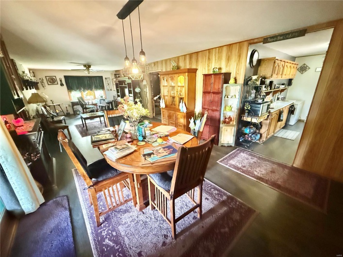 Dining space with a ceiling fan, wood walls, and concrete floors