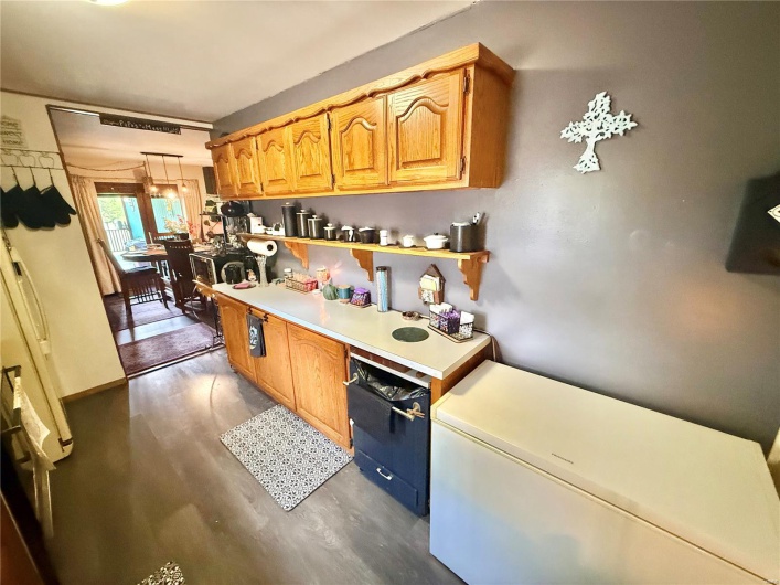 Kitchen featuring light countertops, pendant lighting, refrigerator, and dark wood-style flooring