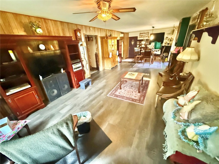 Living room with ceiling fan, wood finished floors, and wooden walls
