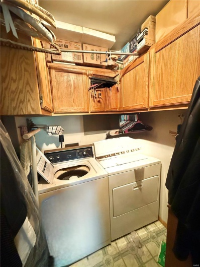 Laundry room featuring light floors, cabinet space, and washer and clothes dryer