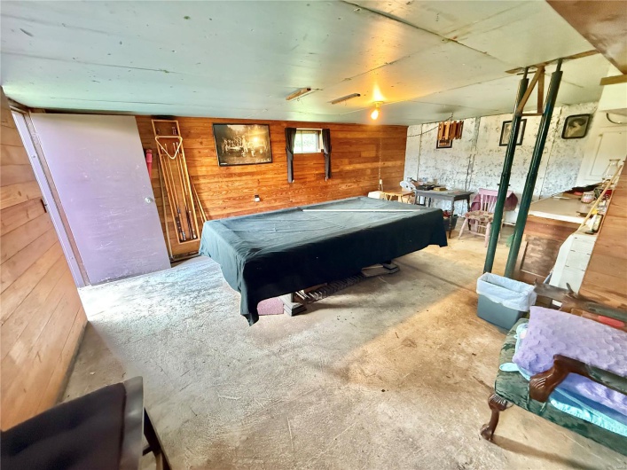 Playroom featuring unfinished concrete flooring, billiards, and wooden walls