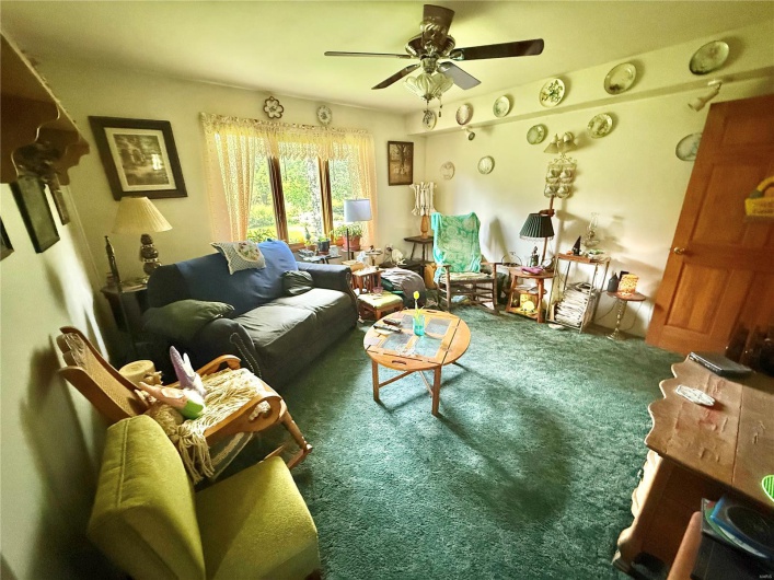 Carpeted living room featuring a ceiling fan