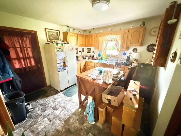 Kitchen with light brown cabinets, a sink, white fridge with ice dispenser, and light countertops
