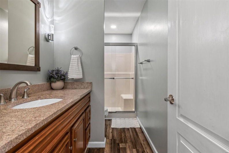 Full bathroom featuring toilet, wood finished floors, a stall shower, vanity, and baseboards