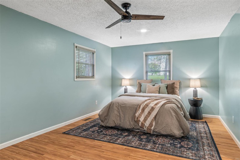 Bedroom with baseboards, a ceiling fan, wood finished floors, and a textured ceiling